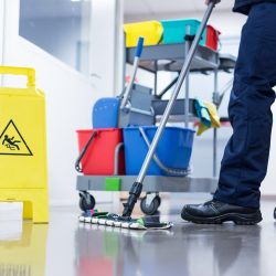 Worker janitor Mopping Floor In Office with trolley